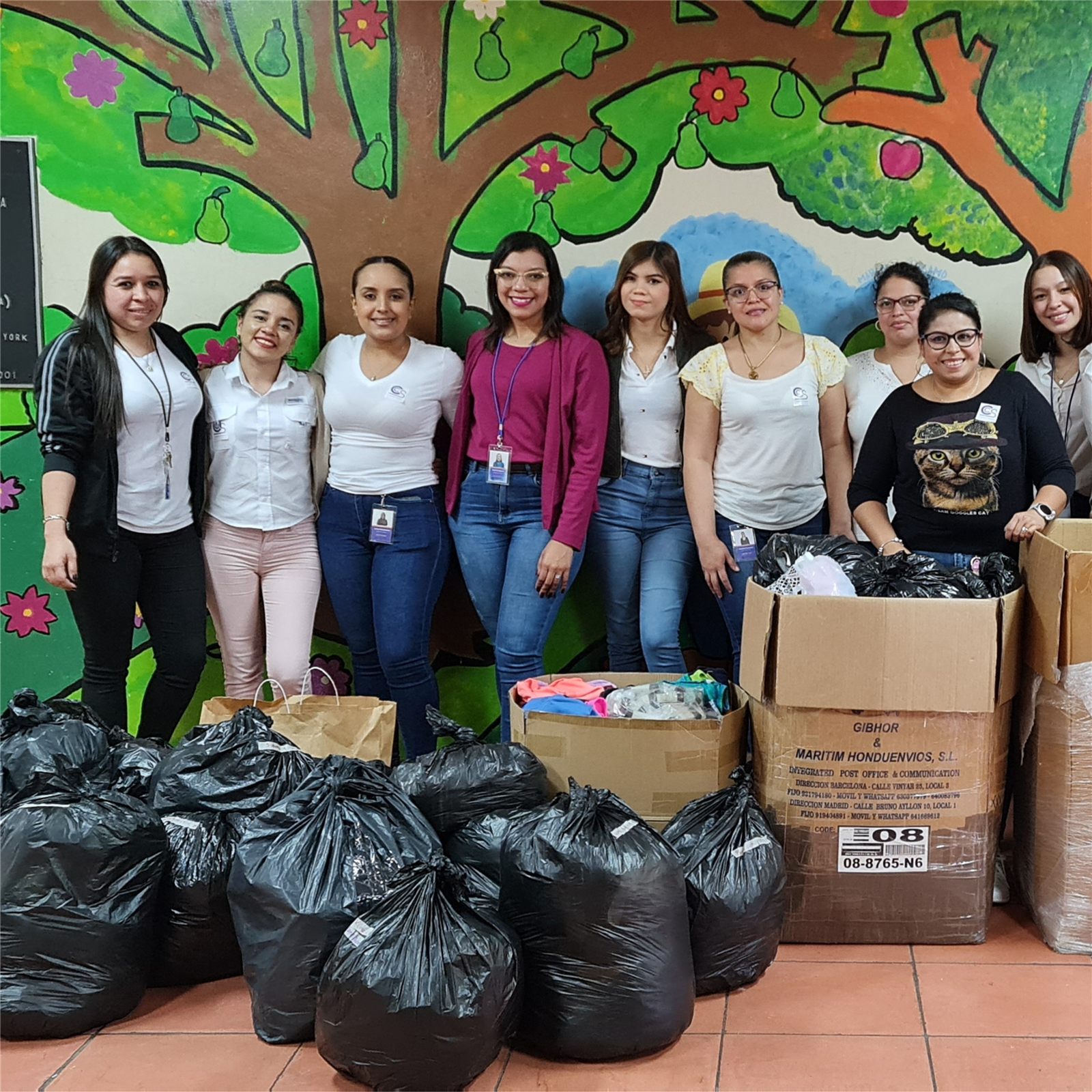 Colaboradoras de CCS entregan donaciones frente a un mural infantil durante una actividad social