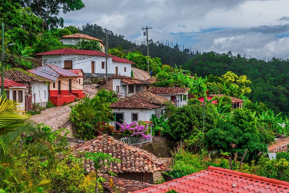 Pueblo colonial hondureño en ladera con techos de teja roja y vegetación tropical