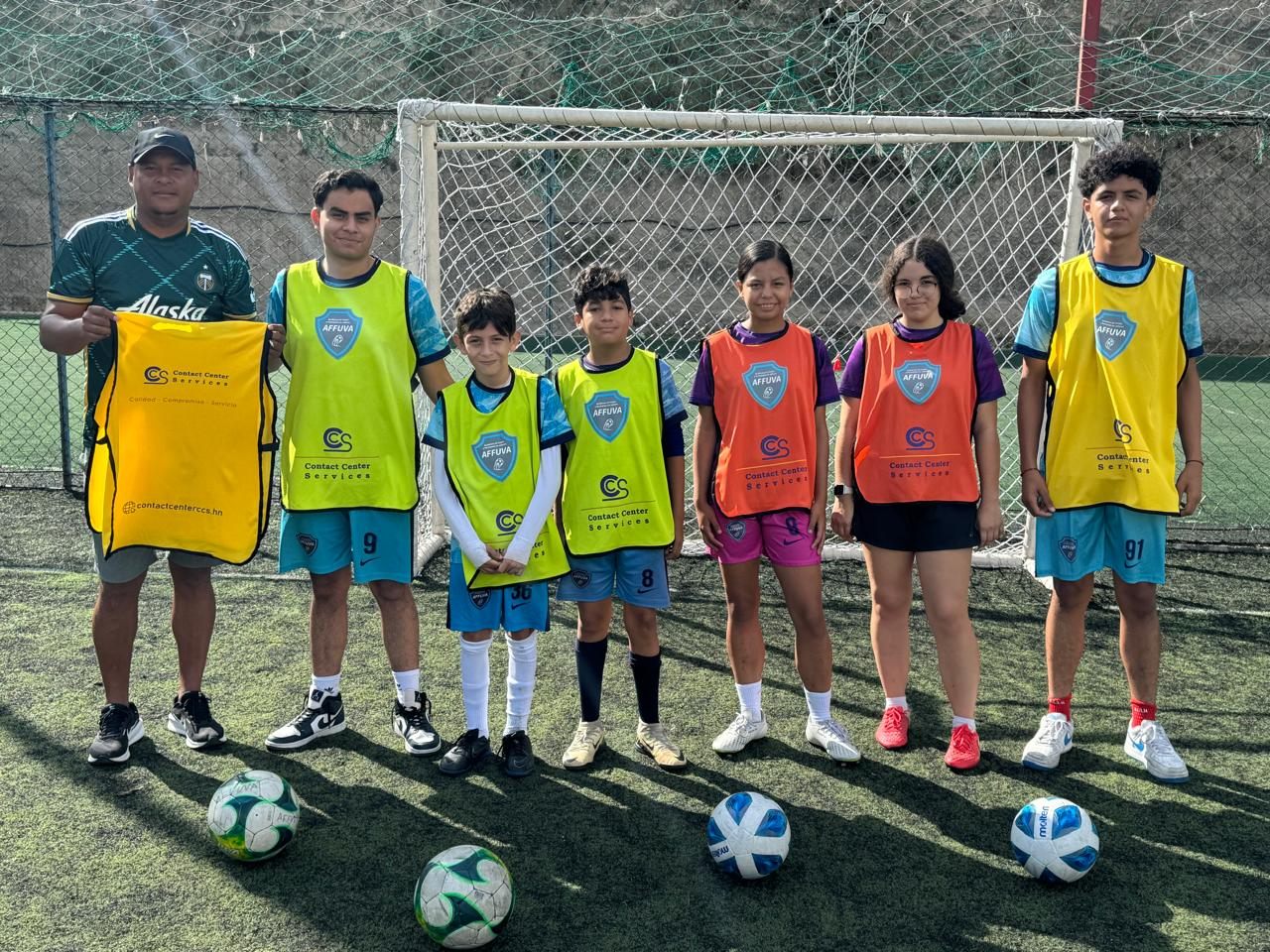 Equipo juvenil de fútbol con chalecos patrocinados por CCS posa con su entrenador